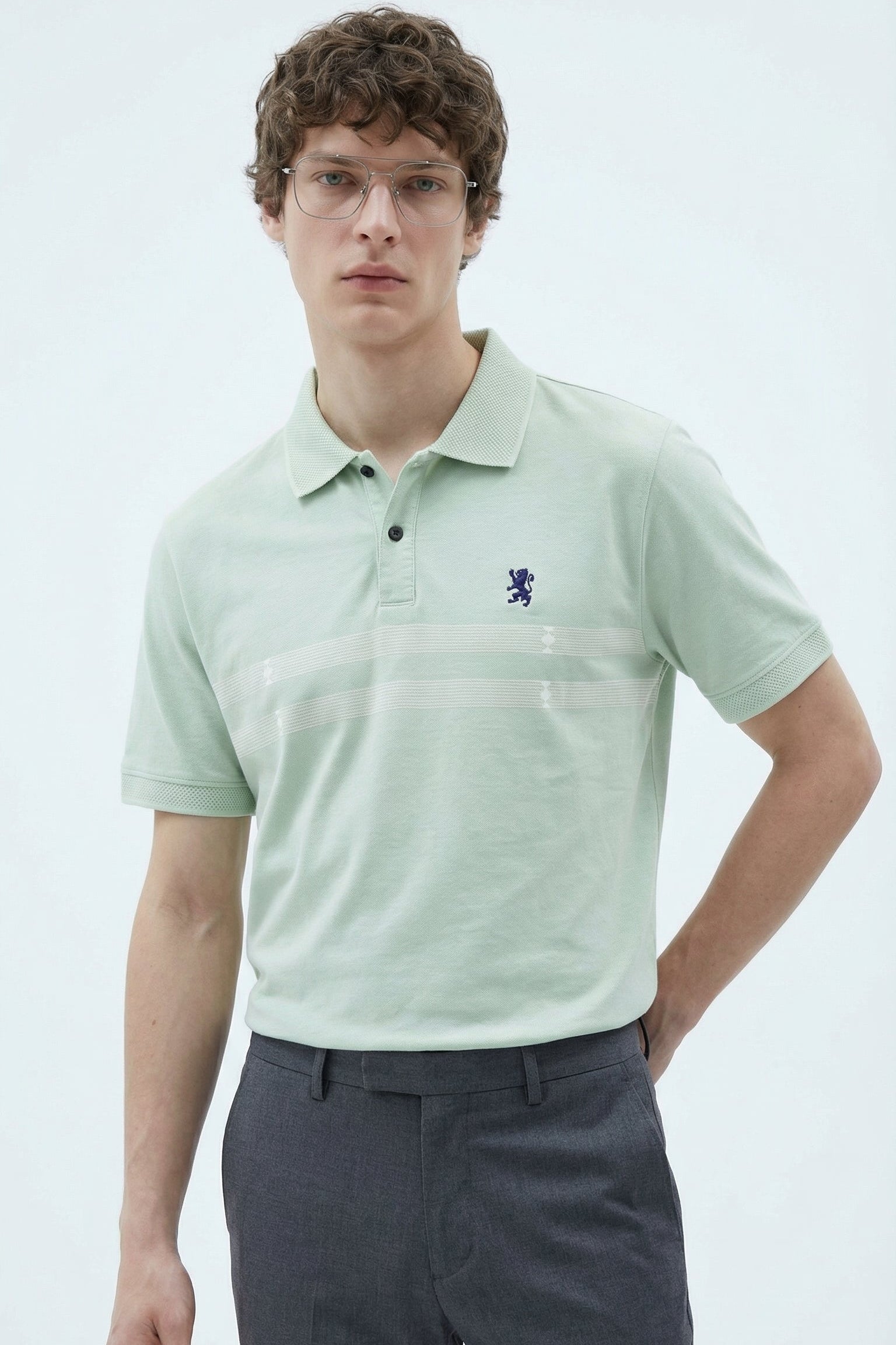 Man wearing a light green polo shirt with a logo on a white background